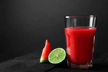 Glass with smoothie and watermelon slice on dark wooden table