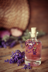 Bottle with aroma oil and lavender flowers on wooden background