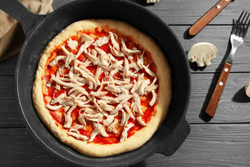 Unbaked pizza in pan on wooden table