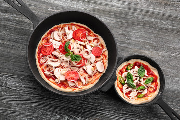Unbaked pizza with mushroom in pans on wooden table