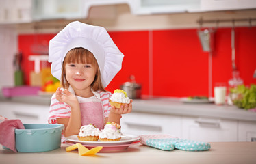 Little girl with cakes in kitchen