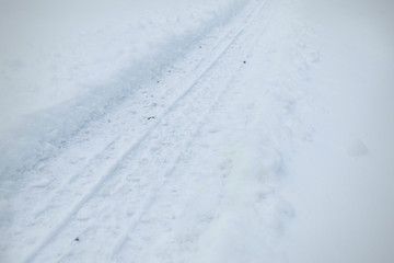 Snowy tire tracks on the winter road. Car tracks on snow city street. 