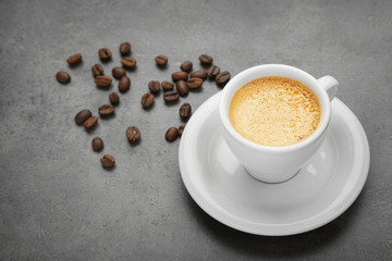 Cup of coffee and beans on grey table
