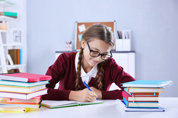 Teenage girl with pile of books sitting at desk in a classroom