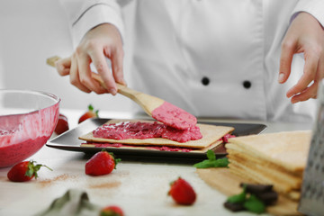 Cooking concept. Professional confectioner making delicious cake with fruit cream, closeup