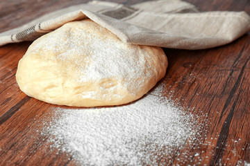 Raw dough and flour on wooden kitchen table