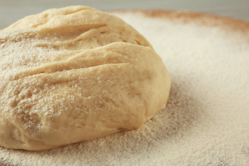 Close up view of raw dough and flour on wooden board
