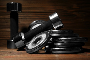 Dumbbells and weight plates on wooden background, closeup