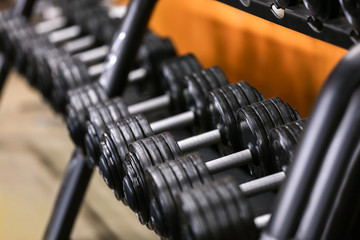 Rack with different dumbbells in gym, close up