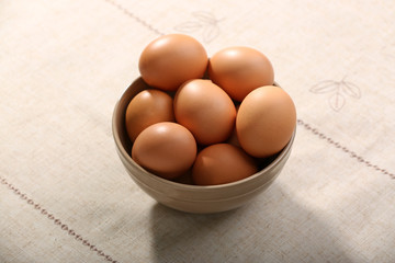 Raw eggs in bowl on tablecloth