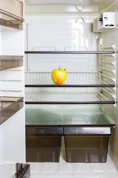 A yellow apple on a shelf in a refrigerator