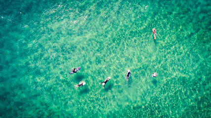 Surfers rest on the surface of the ocean aerial view