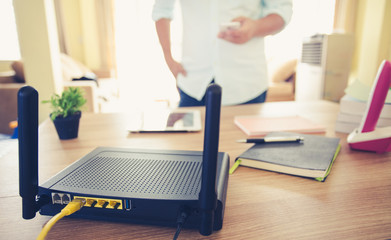 closeup of a wireless router and a man using smartphone on living room at home ofiice