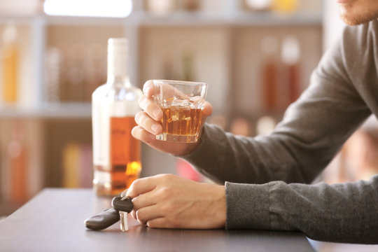 Man sitting in bar with car key and glass of alcoholic beverage. Don't drink and drive concept