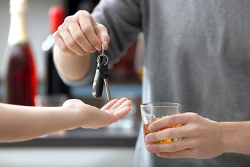 Close up view of drunk man giving car key to woman, on blurred background. Don't drink and drive concept