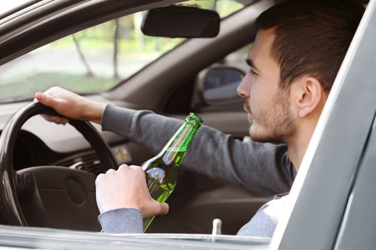 Man drinking beer while driving car. Don't drink and drive concept