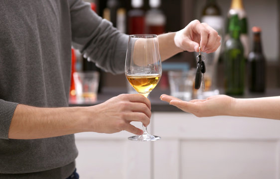 Close up view of drunk man giving car key to woman, on blurred background. Don't drink and drive concept