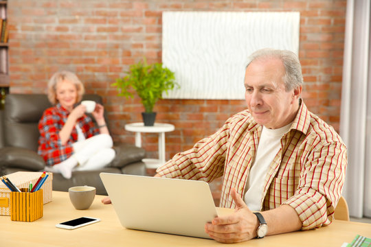 Senior man making video call using laptop at home