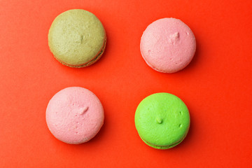 Tasty different colored macaroons on red background
