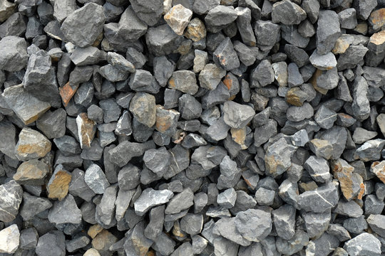aggregate - a stack of gravel / grit consisting of larger dark and light gray coarse stones, crushed and broken at a stone pit to similar size. The colors and shapes are very irregular.