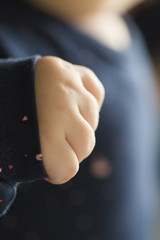 Small white baby fist close up on a blue girl dress