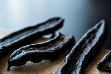 Ripe Carob Pods on wooden surface.