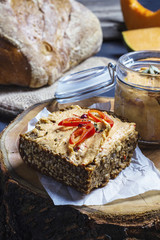 A slice of grainy bread with homemade pumpkin puree, on a wooden