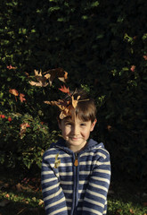 niño lanzando hojas secas en otoño