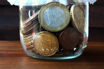 coins faling from glass bottle on the wood table © maria