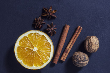 anise, orange, cinnamon sticks and walnuts on a black background