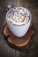 A cup of hot cocoa on a slice of wood