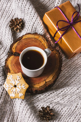 Hot coffee and a christmas present on a grey blanket