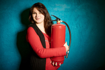 brunette woman in a red blouse standing against the backdrop of a blue wall and holding a fire...