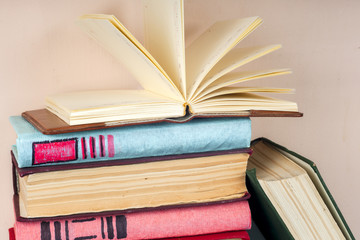 Open book, stack of colorful hardback books on light table. Back to school. Copy space for text