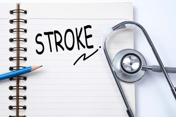 Stethoscope on notebook and pencil with stroke words as medical