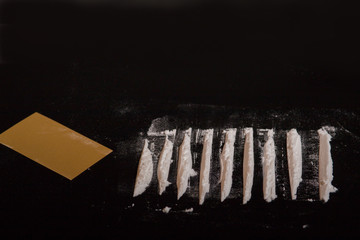 white cutted drug dust with credit card on black background with copyspace