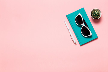Creative flat lay photo of workspace desk with aquamarine notebook, eyeglasses, cactus with copy...