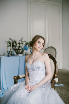 Portrait of young beautiful modern sitting in a armchair bride in a grey lace dress.