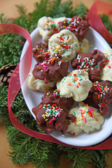 White and milk chocolate nut clusters with sprinkles, a ribbon and seasonal evergreens
