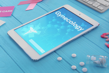 Tablet with word GYNECOLOGY and pills on blue wooden background