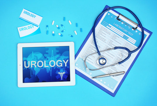 Tablet computer, clipboard, stethoscope and medicines on blue background. Urology concept