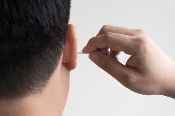 man cleaning ear with cotton bud