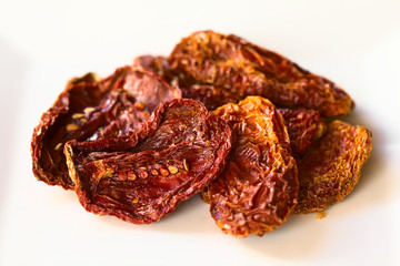 Sun-dried tomato halves on white plate, photographed with natural light (Selective Focus, Focus in the middle of the image)