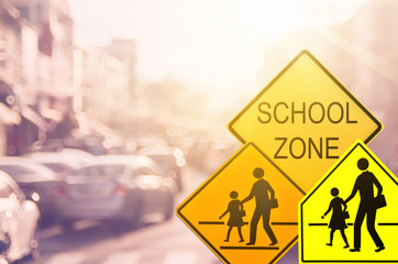 School zone warning sign on blur traffic road with colorful bokeh light abstract background.