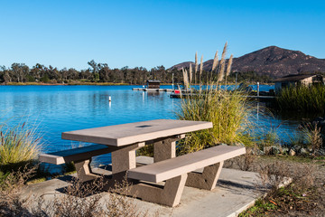 Obraz premium Picnic table at Lake Murray in San Diego, California with boat rental dock and Cowles Mountain in the background, 