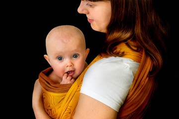 Happy mother with her baby in a sling - isolated on balck