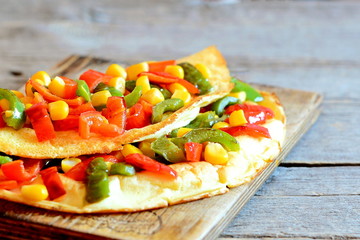 Stuffed omelet on wooden background with copy space for text. Healthy fried omelet stuffed with red and green bell peppers and canned corn. Vegetarian breakfast omelet recipe. Rustic style. Closeup