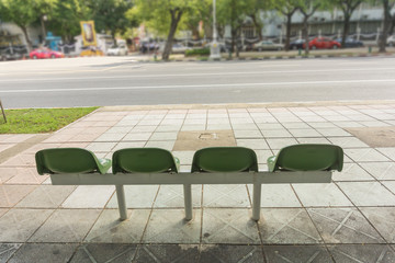 empty green chair at the public bus stop on the footpath.