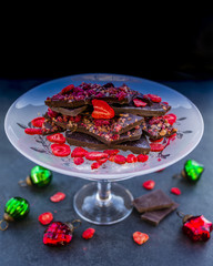 Dessert dark chocolate with dried raspberries and strawberries with Christmas decoration on a stone background. 