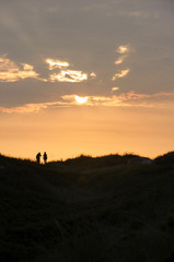 Naklejka na ściany i meble Two people enjoying the sunset at the North Sea